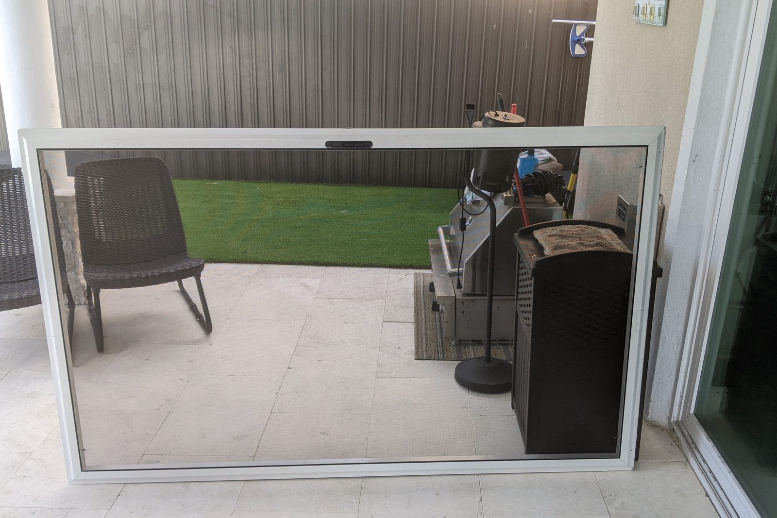 Sliding screen door panel lifted out of its track and leaning against the patio wall during a repair