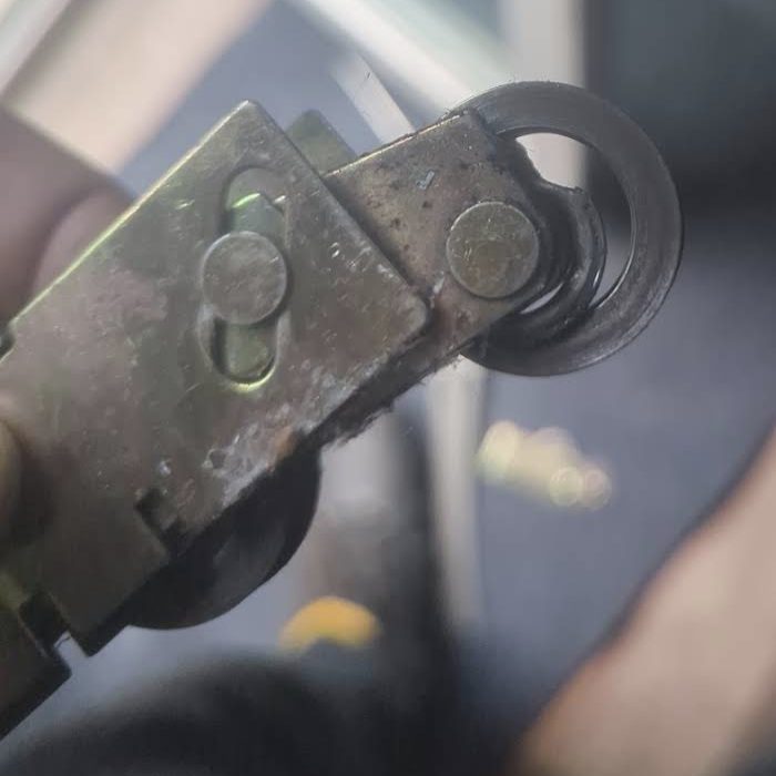 Failed builder-grade sliding glass door roller removed from a Charlotte door, showing an empty bearing race where the ball bearings have rusted apart and fallen out